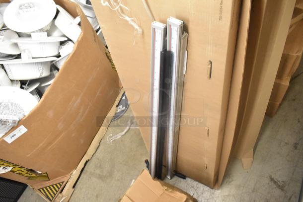 Two metal pieces with measuring scales, leaning against a cardboard box. Good condition, suitable for measurement tasks.