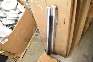 Two metal pieces with measuring scales, leaning against a cardboard box. Good condition, suitable for measurement tasks.