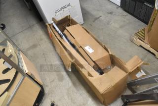 Open cardboard box on concrete floor, partially damaged. Contains metal rods and wires. Label reads "203". Background shows other industrial items.