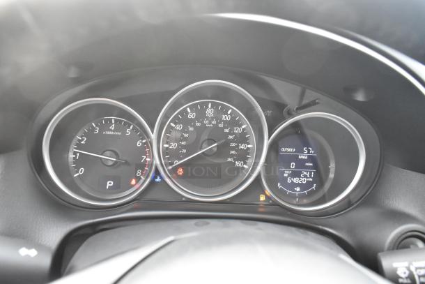 Dashboard of a 2016 Mazda CX-5 Grand Touring showing 64,820 miles. Odometer and gauges in focus; exterior temperature 57°F.
