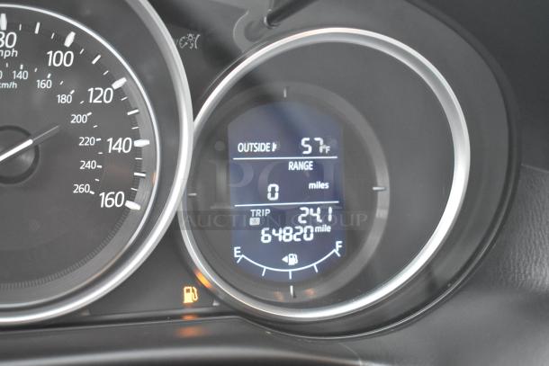 Close-up of the 2016 Mazda CX-5 Grand Touring SUV odometer displaying 64,820 miles. Temperature reads 57°F. Clean condition.