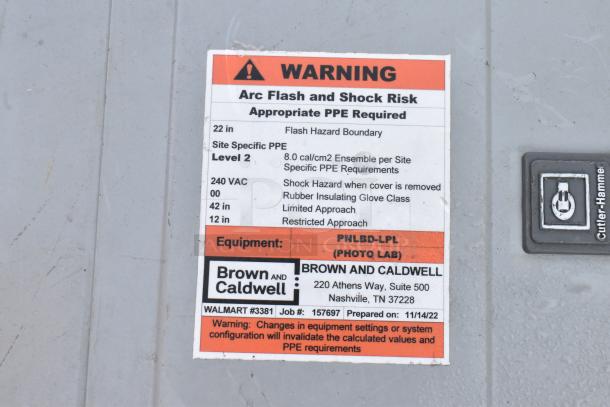 Gray metal electrical box with warning label indicating arc flash risk. Contains Cutler-Hammer logo and Brown and Caldwell info.