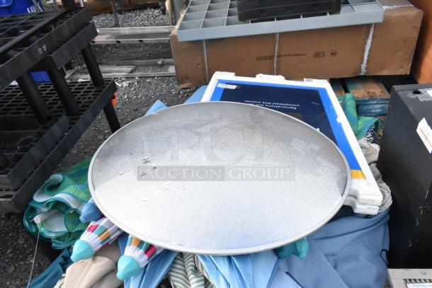 Pallet lot featuring assorted items including umbrellas, a large circular metal tray, and various containers, in used condition.
