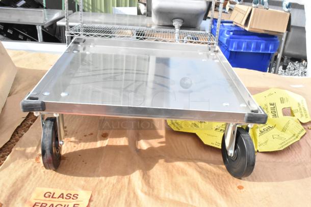 Metal dolly with four wheels shown on a surface with fragile labels. Appears new, part of auction lot.