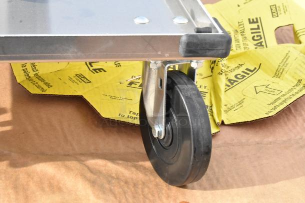 Metal dolly wheel close-up on yellow "Fragile" ULINE packaging material. New condition, sturdy construction.