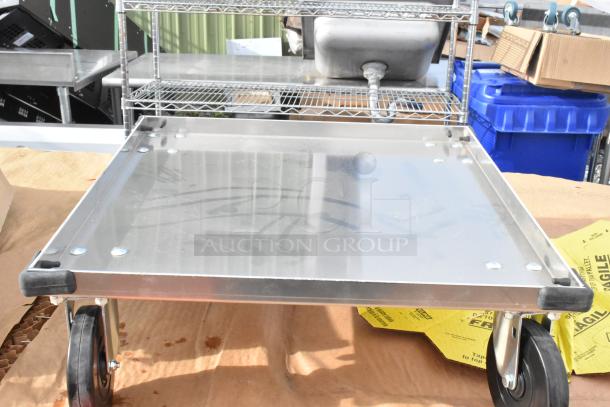Alt text: Metal dolly, part of a scratch and dent auction lot. Features sturdy wheels and a flat surface for transport.