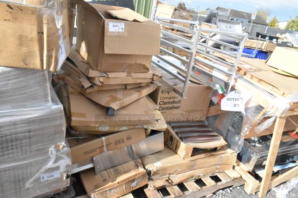 Stack of new scratch and dent items including aluminum bun pan rack, paper cup lids, distressed copper table, on pallets.