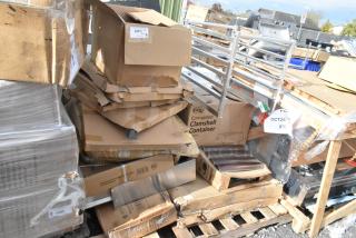 Stack of new scratch and dent items including aluminum bun pan rack, paper cup lids, distressed copper table, on pallets.