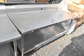 Win-holt stainless steel table with under shelf and back splash. Gently used condition with visible scuffs. Sturdy design.