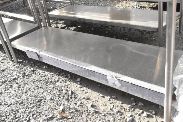Win-holt stainless steel table with an under shelf and backsplash. Slight wear, ideal for kitchen use.