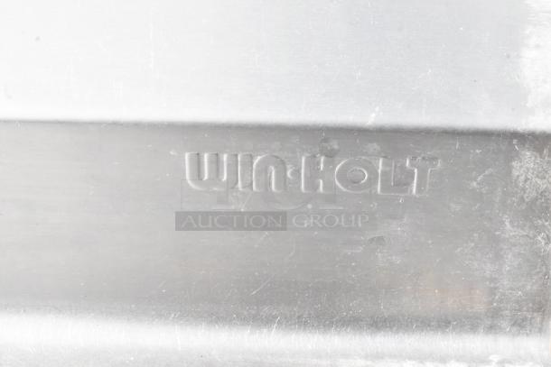 Win-holt stainless steel table detail, showing embossed brand logo on sturdy surface, indicating durable construction.