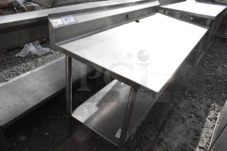 Win-holt stainless steel table with under shelf and back splash. Features durable construction, suitable for kitchens.