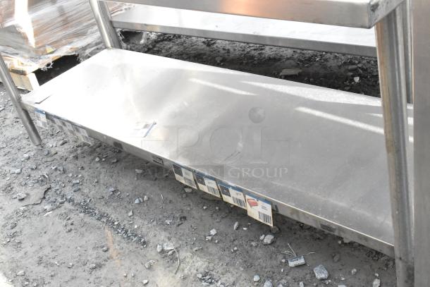 Win-holt stainless steel table with under shelf and back splash. Durable construction, shows minor wear. Suitable for kitchen use.