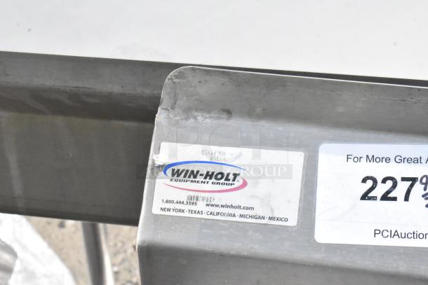Win-holt stainless steel table with under shelf and back splash. Visible labels include company info and auction details.