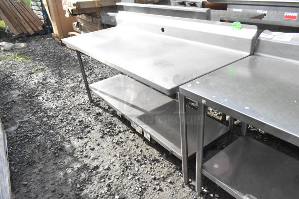Win-holt stainless steel table with under shelf and back splash, used condition, minor surface scratches, ideal for industrial use.
