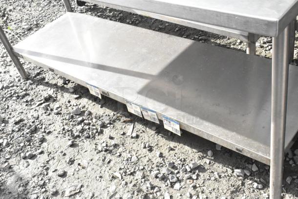 Win-holt stainless steel table with undershelf and backsplash, sturdy construction, light wear, ideal for commercial kitchens.