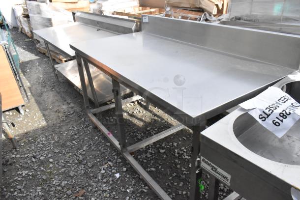 Win-holt stainless steel table with back splash, durable design, used condition, ideal for commercial kitchens.