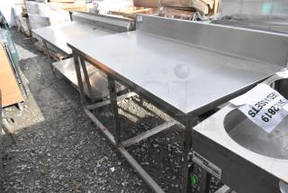 Win-holt stainless steel table with back splash, durable design, used condition, ideal for commercial kitchens.