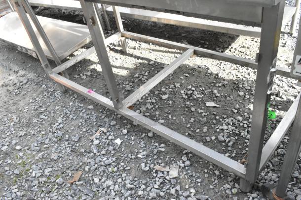 Win-holt stainless steel table with backsplash, sturdy construction. Shows outdoor storage wear. Ideal for commercial use.