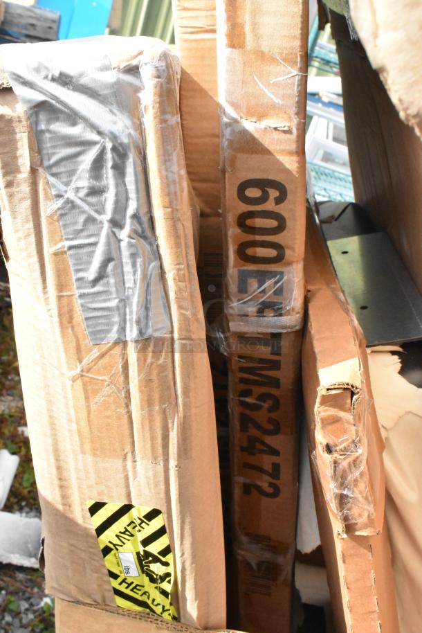 Cardboard packaging showing visible markings for a hood filter and heavy items, indicating new scratch and dent items including tables and a changing station.