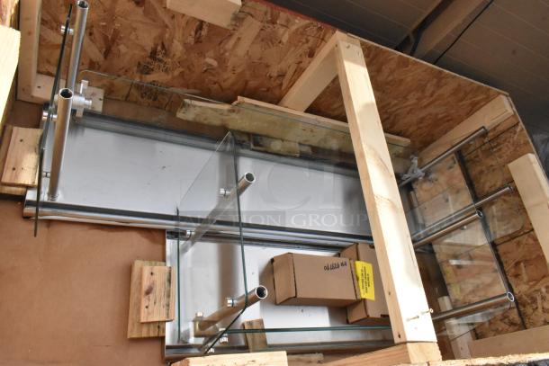 Crate containing two brand new sneeze guards, stainless steel and glass, scratch and dent condition, with packaging materials.