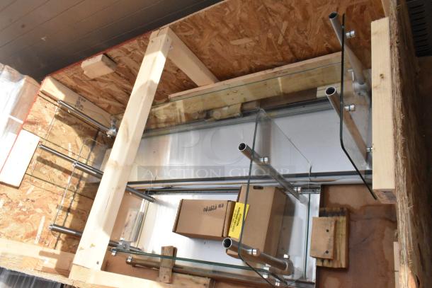 Crate containing 2 brand new sneeze guards with minor scratches and dents. Metal frame, glass panels included.