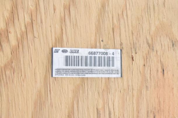 Label on wooden surface showing barcode and numbers "66877008 - 4" indicating shipment details.