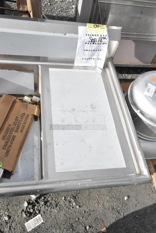 Brand new Regency 600S32030220 stainless steel 3 bay sink with dual drain boards, minor scratches, label for "Sep 18th" visible.