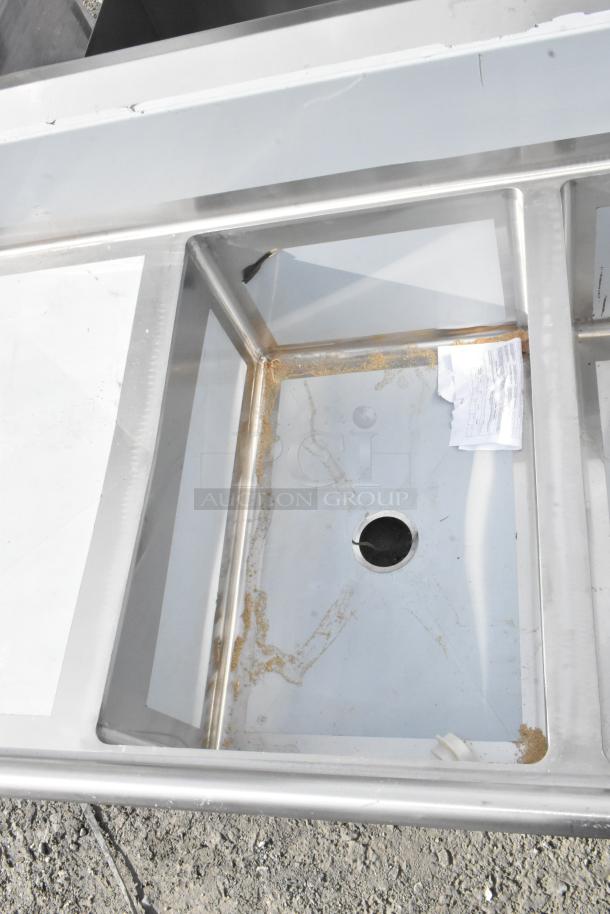 Brand new Regency 600S32030220 stainless steel 3 bay sink with dual drain boards, minor scratches visible.