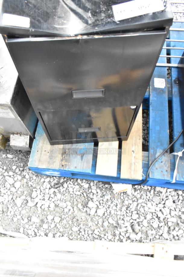 Black two-drawer filing cabinet on a pallet, included with BAVFM mini cooler and metal rack. Industrial setting, visible wear.