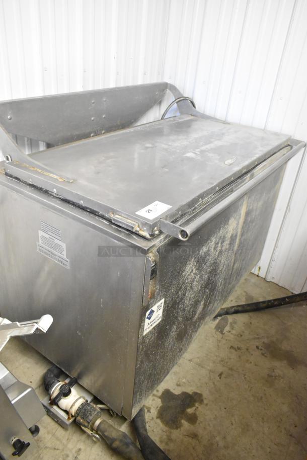 Stainless steel commercial floor style washing bin with visible markings and pipes, in used condition.