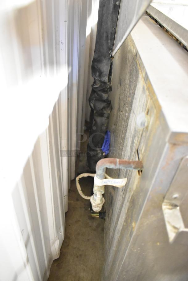 Stainless steel commercial floor washing bin with visible wear, featuring a water inlet valve and attached black pipe.