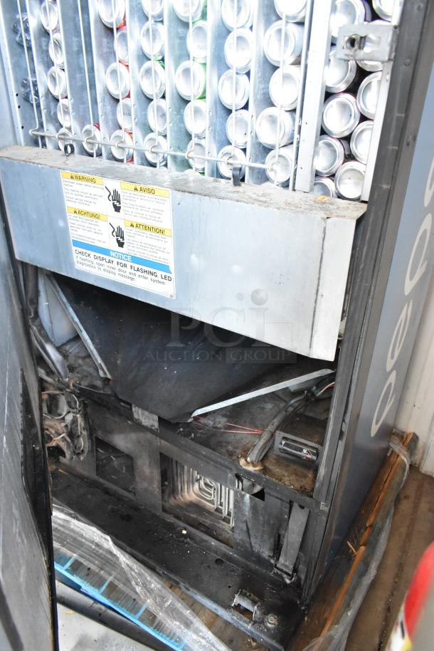 Dixie-Narco DN600E-MC/SII-9 commercial vending machine with visible cans, warning labels, and credit card acceptor. Used condition.