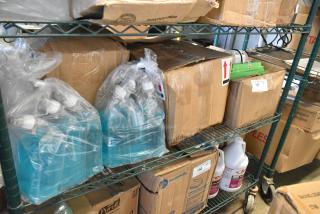 Boxes and bottles of various items, including Betco AF315 disinfectant cleaner. Items are on a metal shelf, in used condition.