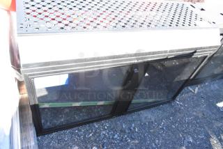 Metal 2 Door Cabinet with glass doors and perforated metal top, shown outdoors on gravel.