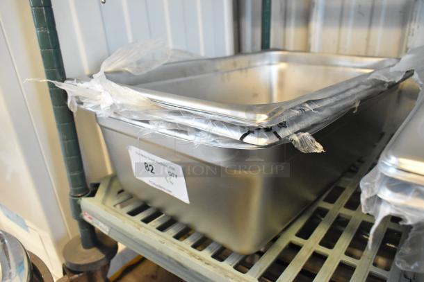 Six new stainless steel drop-in bins with minor dents, wrapped in plastic. Auction label marked "82 QTY 16" visible.