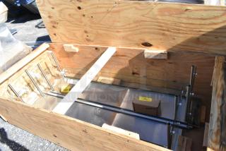 Brand new sneeze guard in crate, metal frame, minor scratches and dents visible. Includes hardware box.