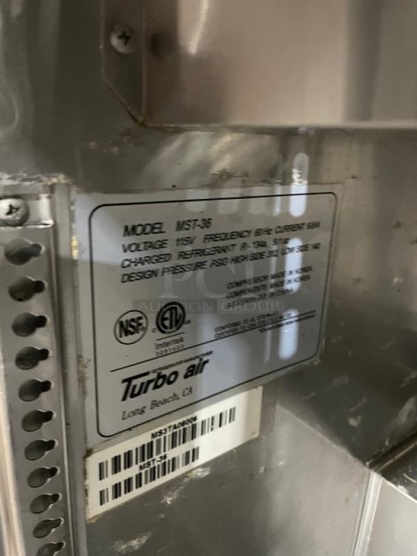 Turbo Air MST-36 stainless steel 2-door refrigerated prep table, poly coated rack, 115V, on casters, tag visible.