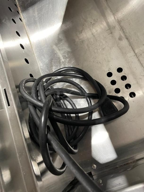 Coiled black power cord on stainless steel surface inside Everest EPBNR1 refrigerated prep table.