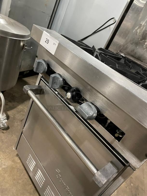 Sunfire commercial stainless steel 4-burner range/oven combo with backsplash, overhead shelf, and wired oven rack. Natural gas powered, on legs.