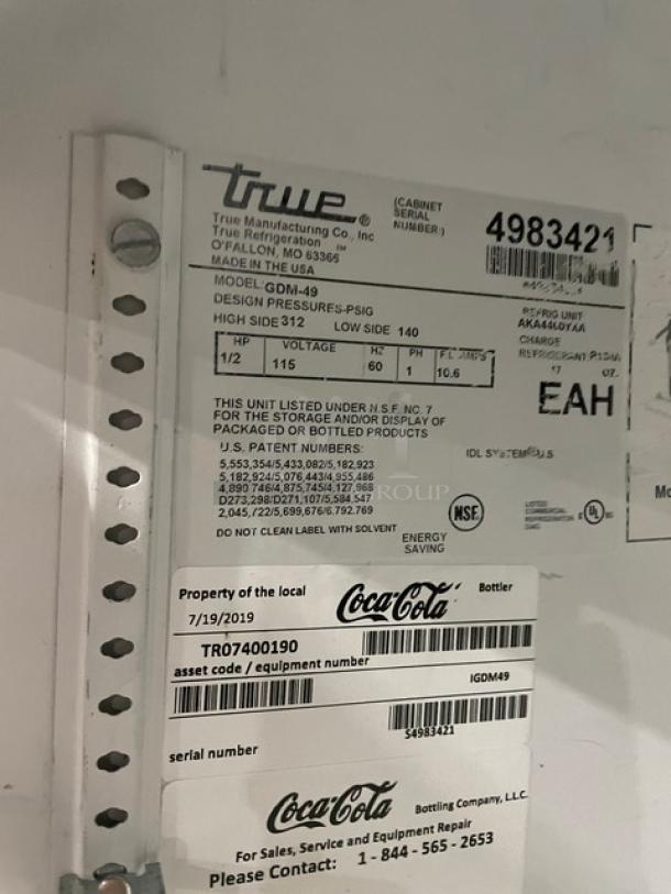 True GDM-49 Commercial Refrigerator tag; SN: 4983421, 115V, 1 Phase, Coca-Cola branding, NSF certified, for bottle storage.
