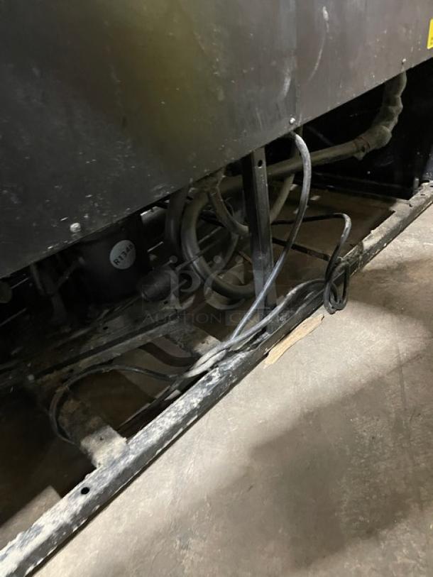 True GDM-49 commercial refrigerator base, showing wiring and components. Black finish with wear, model number visible.