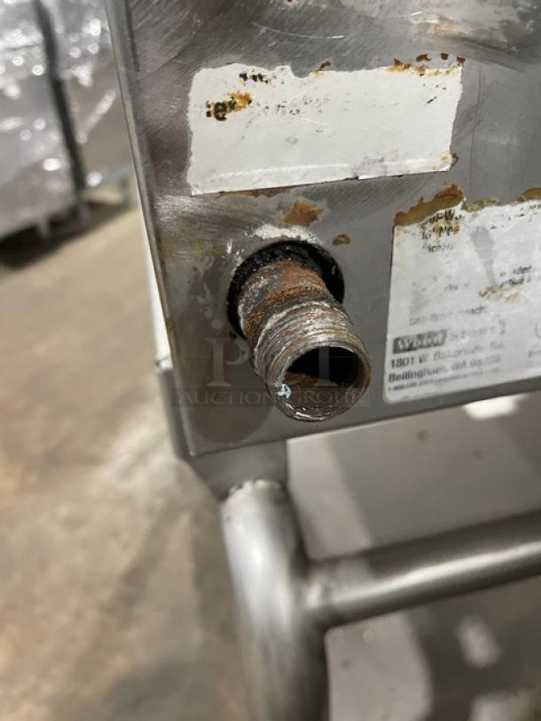 WoodStone stainless steel natural gas plancha griddle connection detail, shows rust and wear, with partial label nearby.