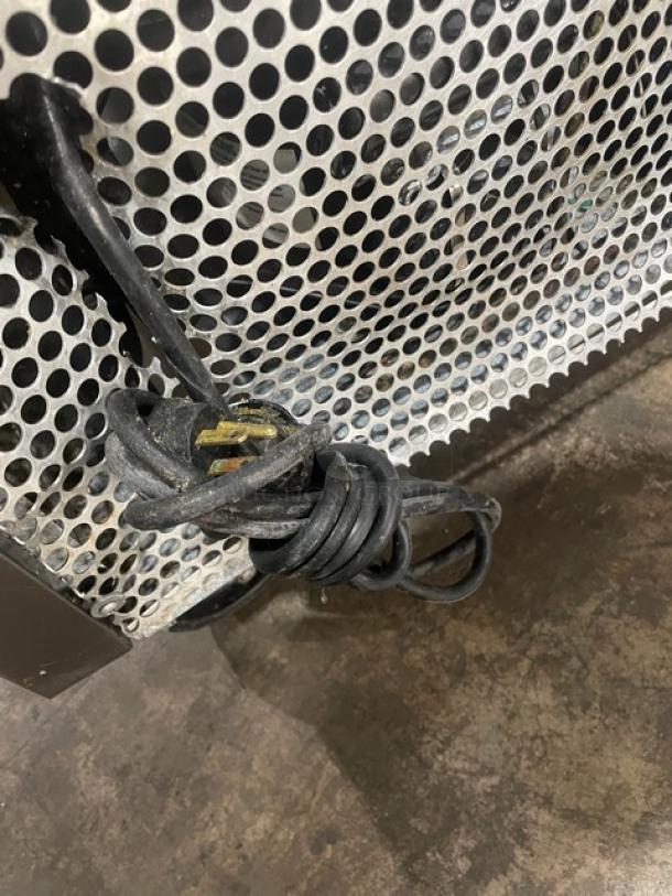 Coiled power cord of a True TSSU-27-08D-2 refrigerated prep table on a textured metal base.