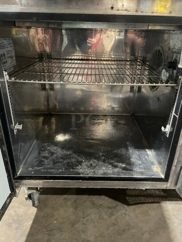 Turbo Air TPR44SD stainless steel refrigerated pizza prep table interior, with chrome plated wire rack, on casters.