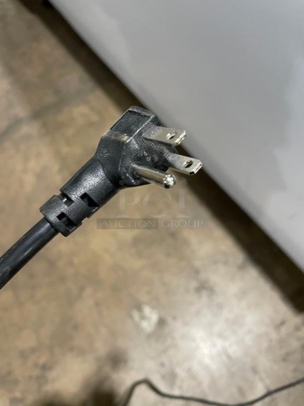 Avantco 360DFF20HCL freezer power plug, standard three-prong type, shown on hardwood floor, indicating 115V compatibility.