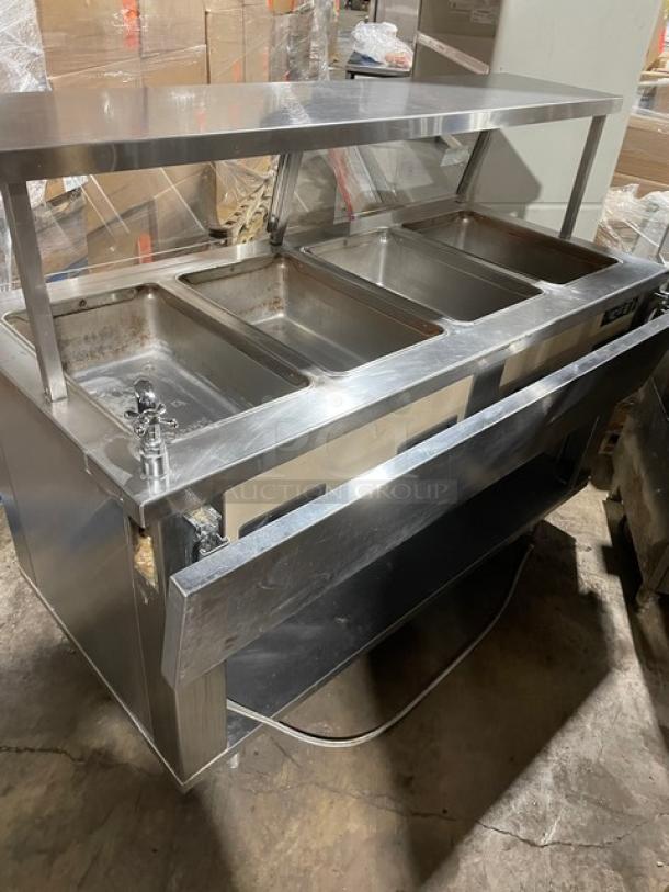 Piper Products stainless steel 4-well hot food serving counter, Model 4HF, with sneeze guard, tray slides, and enclosed shelf.