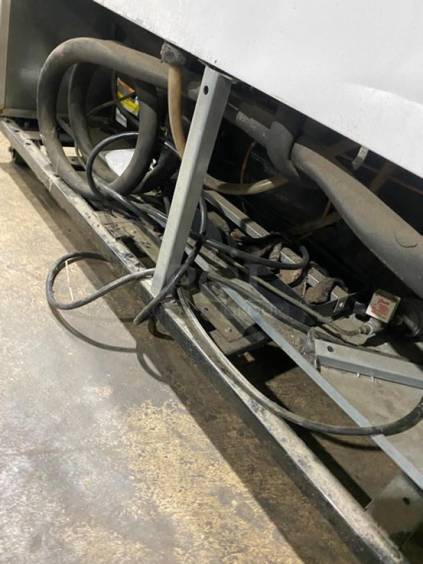 Cables and hoses at the base of a True Commercial Double Glass Swing Door Reach-In Merchandiser Freezer, Model GDM-49F-LD.