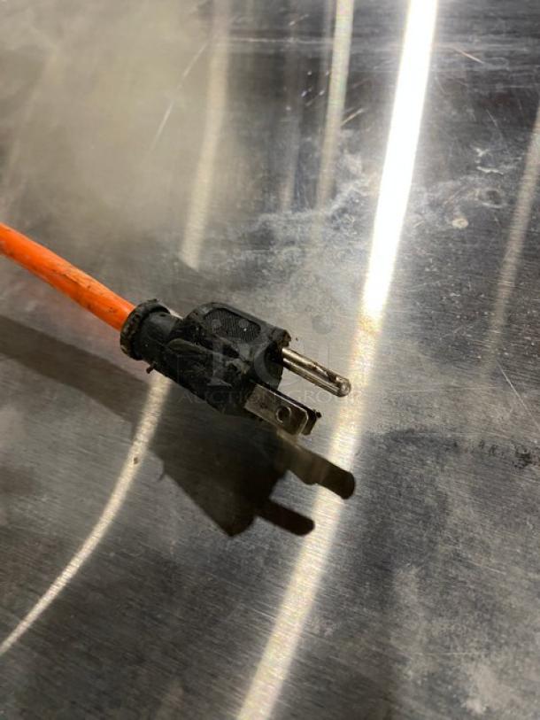 Image showing an orange power cord with a two-prong plug on a stainless steel surface.