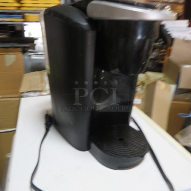 Black Keurig coffee brewer, single serve. Features include removable drip tray. Condition appears gently used.